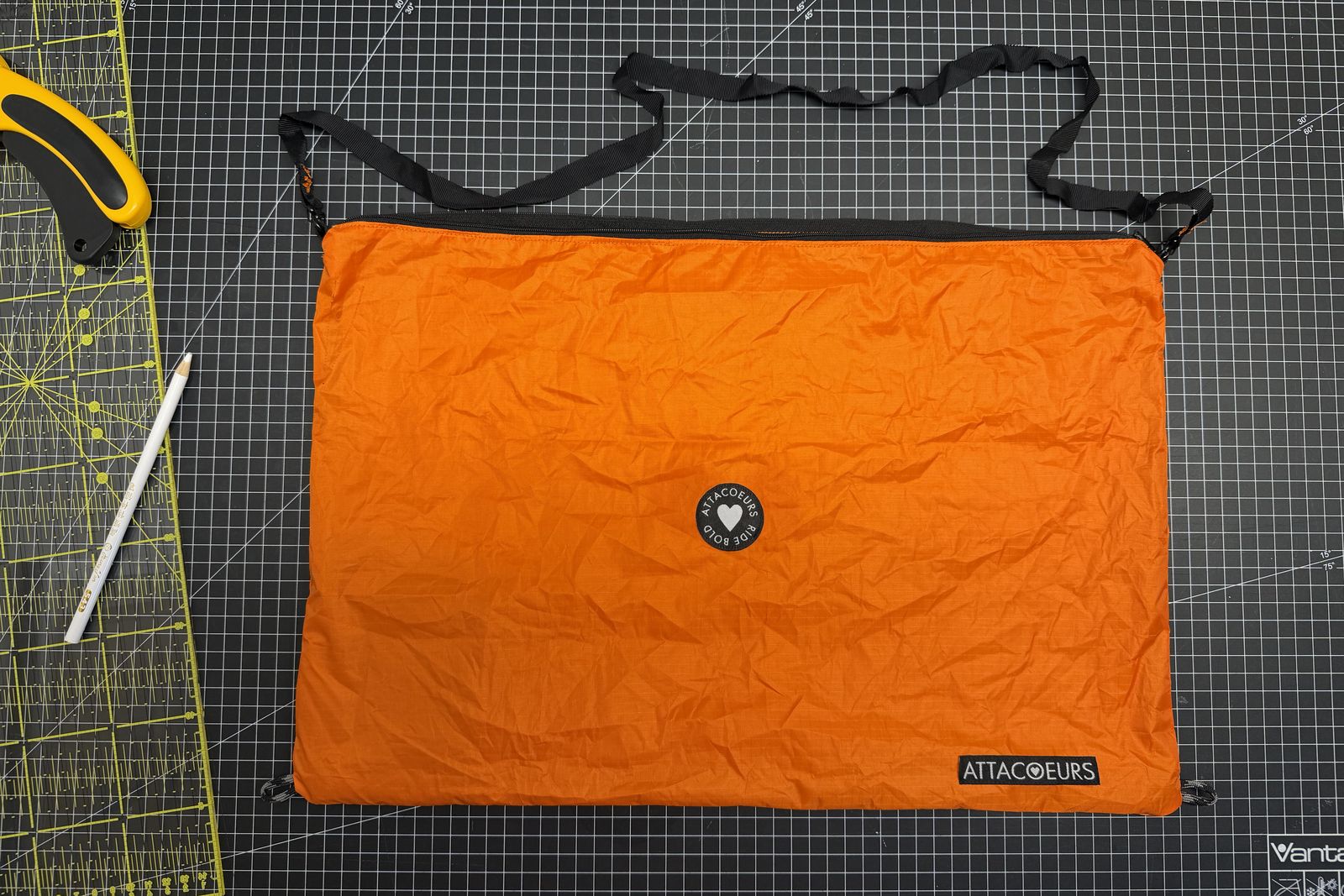 The musette flat on a cutting mat, zip along the long edge, webbing strap beside it