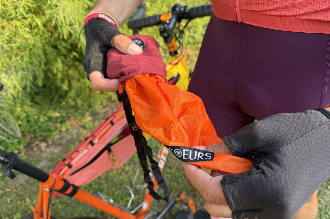 Hands pulling the orange musette out of its stuff pouch